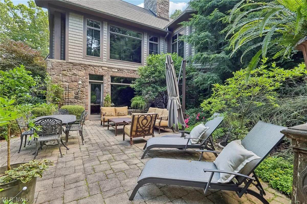 Outdoor living space with metal sun loungers, a matching dining set, and cushioned sofas over concrete flooring.