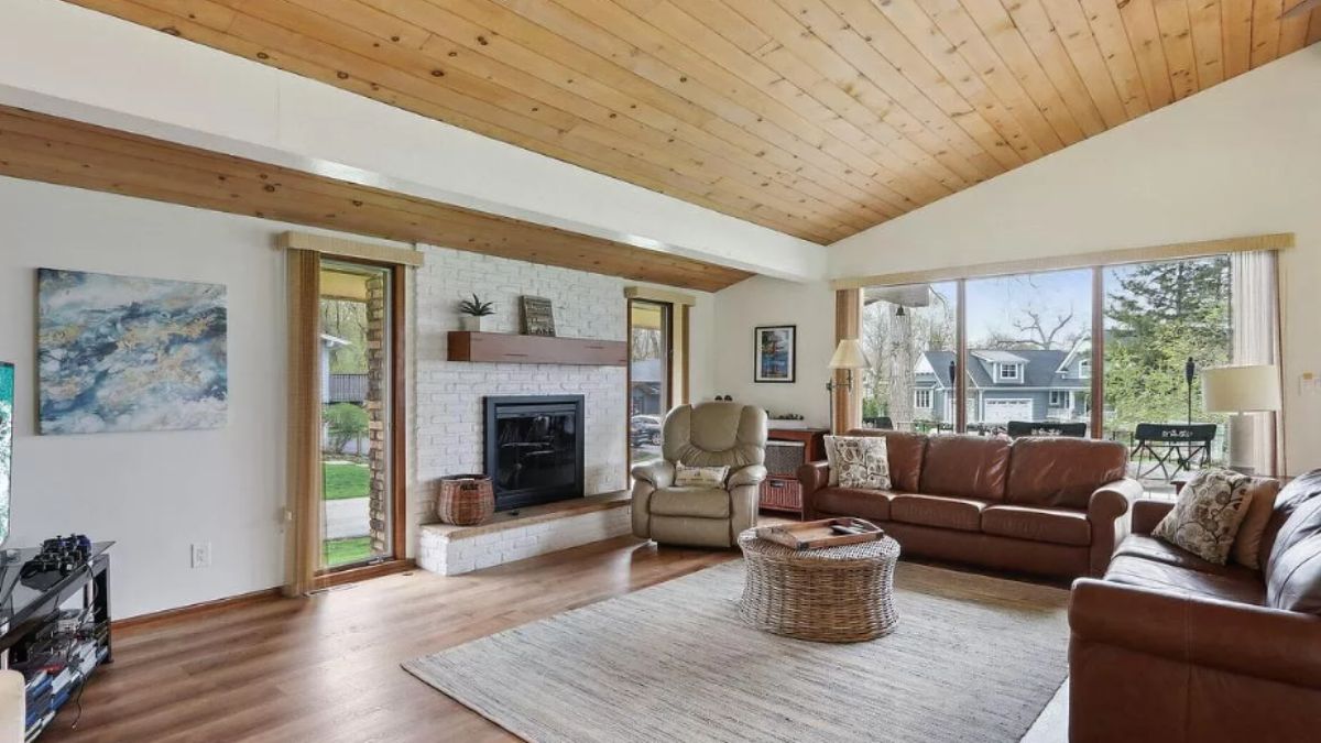 A living room with a wooden floor, rug, couches, center table, and fireplace.