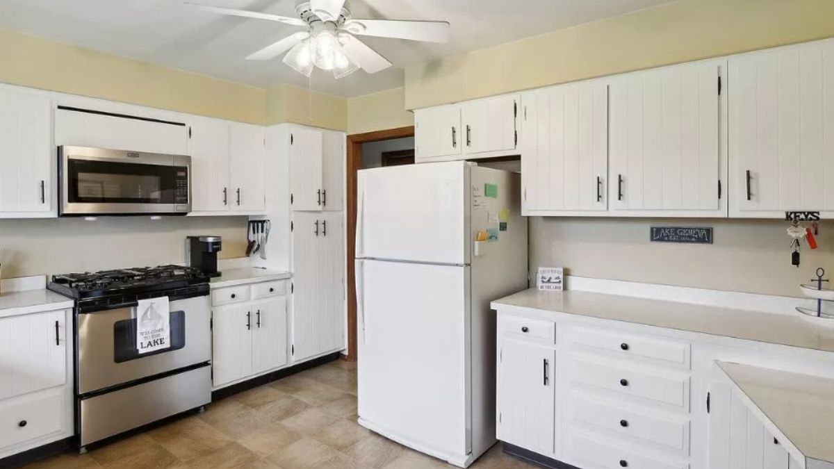 A kitchen with tiled floor, ceiling fan, countertops, cabinets, and kitchen appliances.