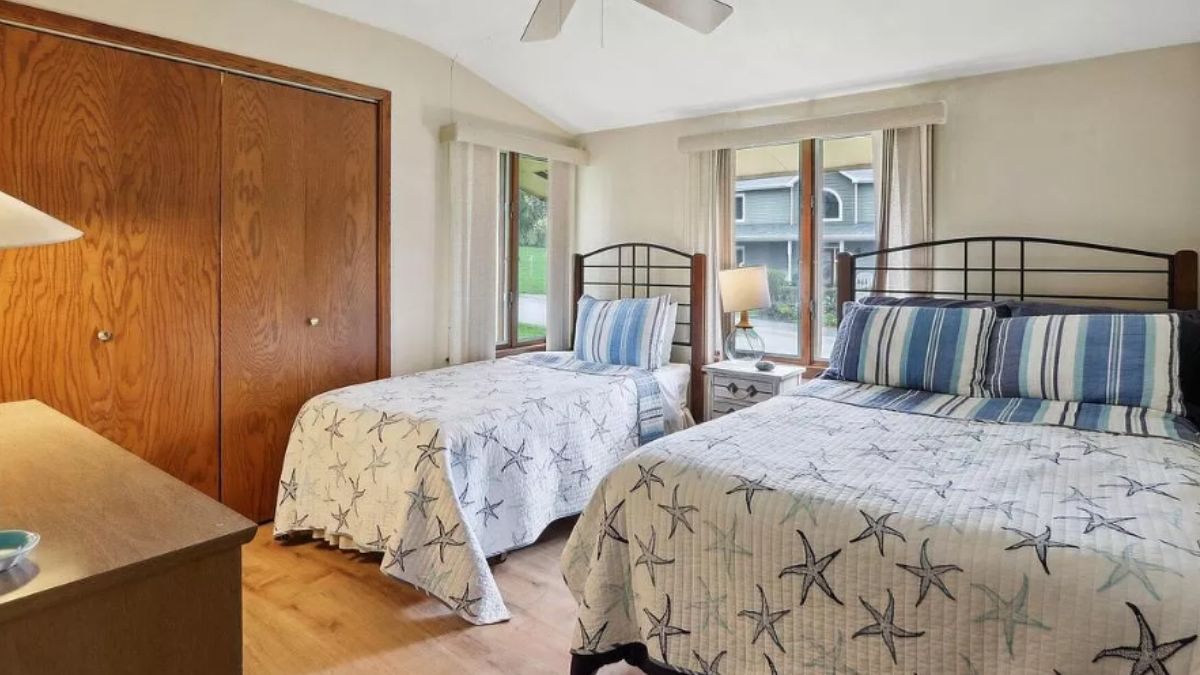 A bedroom with two beds, a window, and a nightstand.