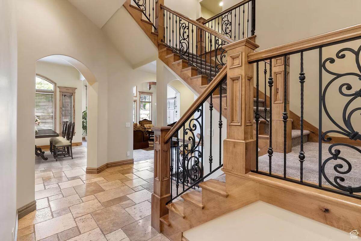 Staircase with carpeted steps and ornate wrought iron railings.