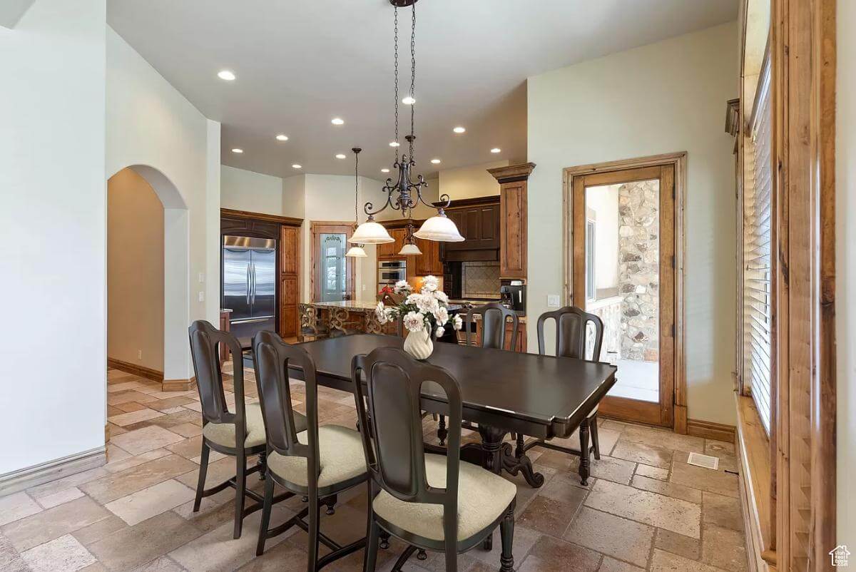 Dining room with a dark wood dining set illuminated by a warm chandelier.