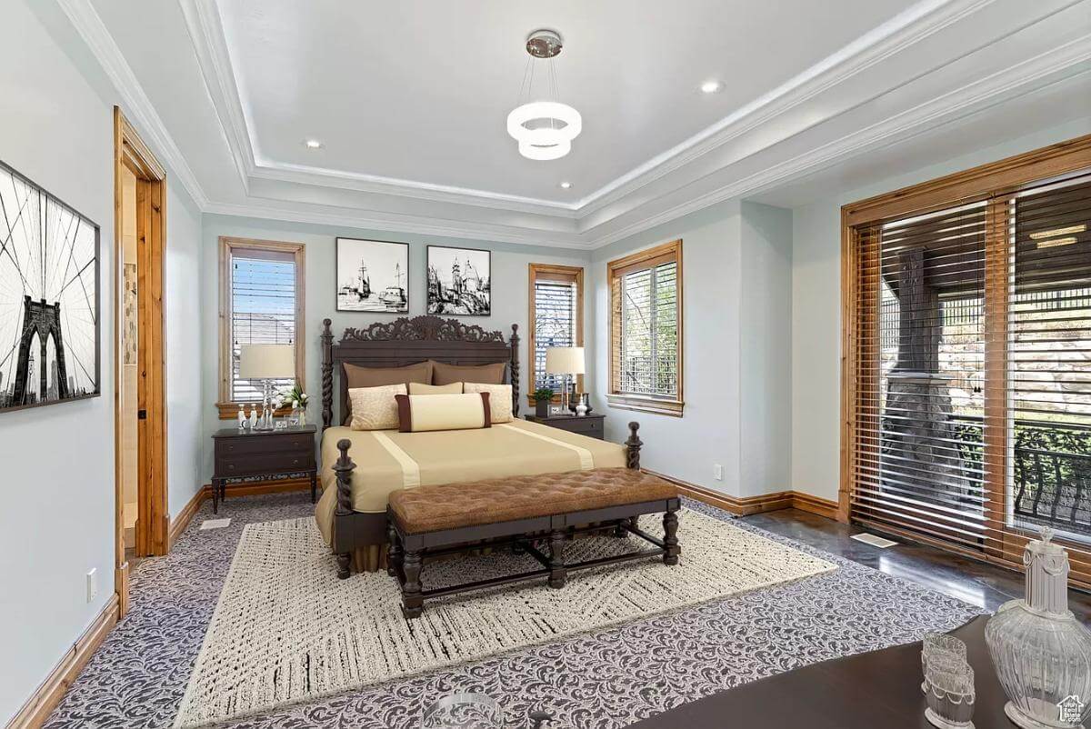 Primary bedroom with a dark wood bed and a tufted bench under a tray ceiling.