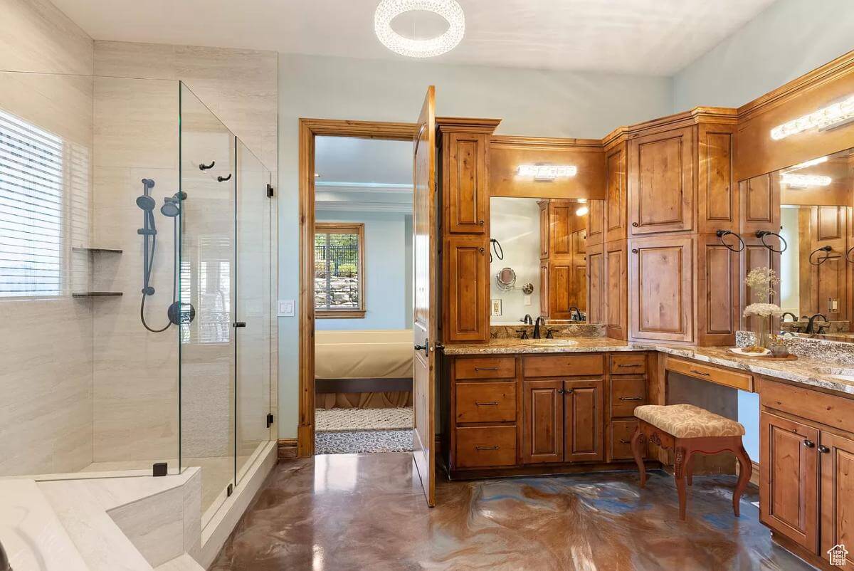 Primary bathroom with a tiled shower and a dual sink vanity with a makeup counter in the middle.