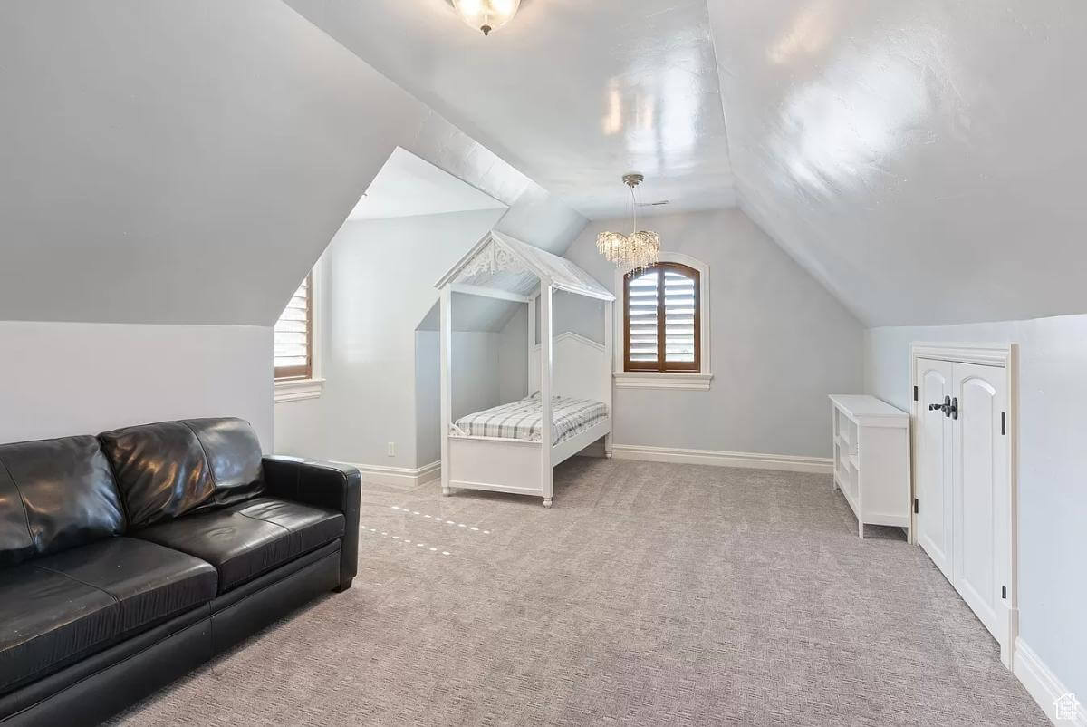 Bedroom with a single custom bed and a black leather sofa under a vaulted ceiling.