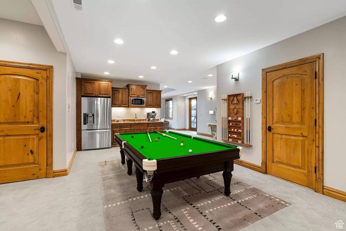 Rec room with a wet bar and a billiards table over the area rug.