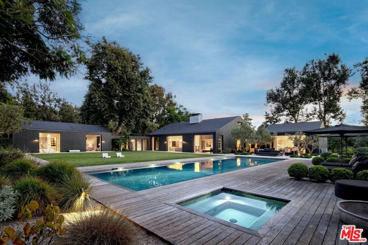 A swimming pool with a jacuzzi, plants, and surrounded by trees.