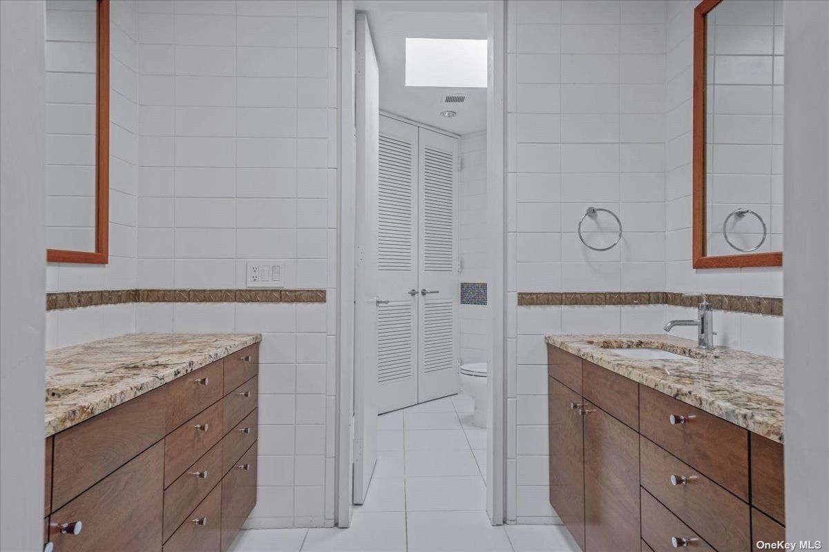 A bathroom with countertops, sink, cabinets, and toilet.