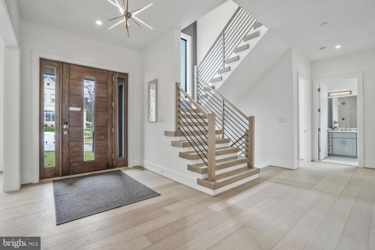 A foyer with a wooden floor, rug, and staircase.