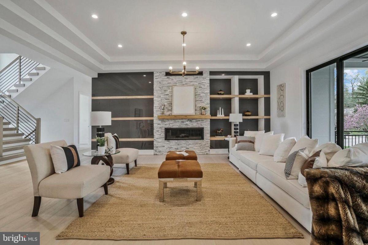 A living room with a fireplace, shelves, chairs, couch, rug, and coffee table.