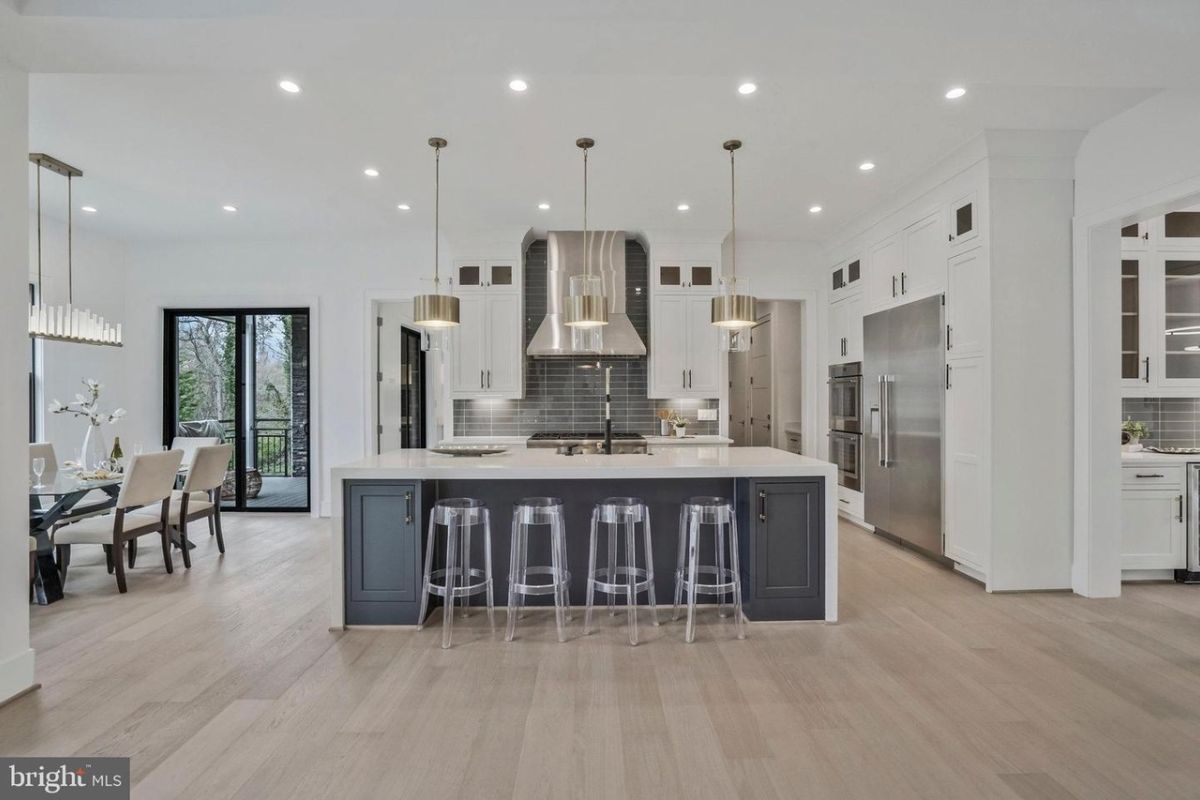 A kitchen with an island, countertop, chairs, and sink.