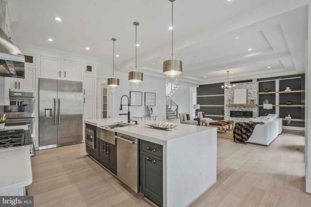 A kitchen with an island, countertop, chairs, kitchen appliances, and a sink.