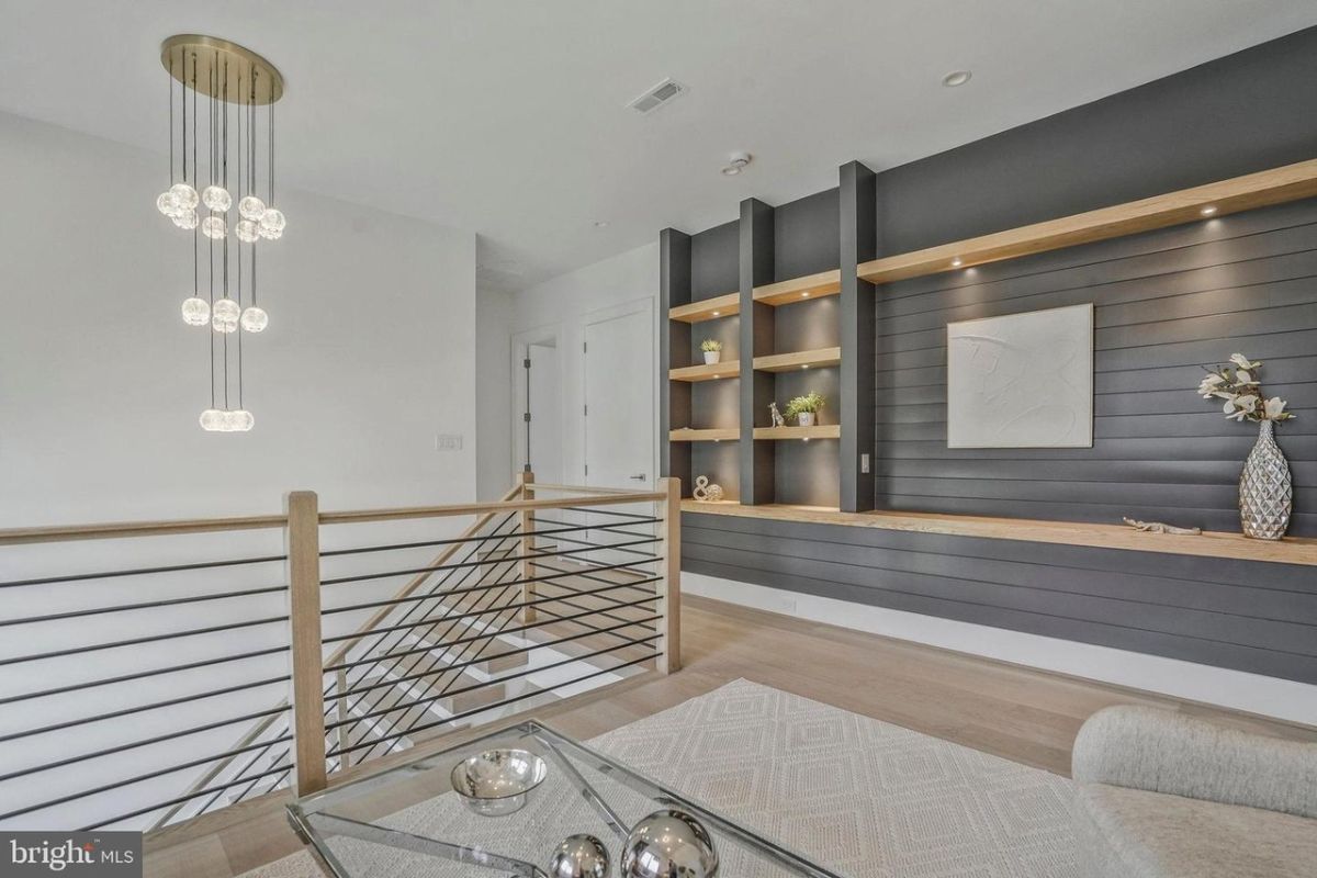 A landing with a shelf, rug, and glass coffee table.