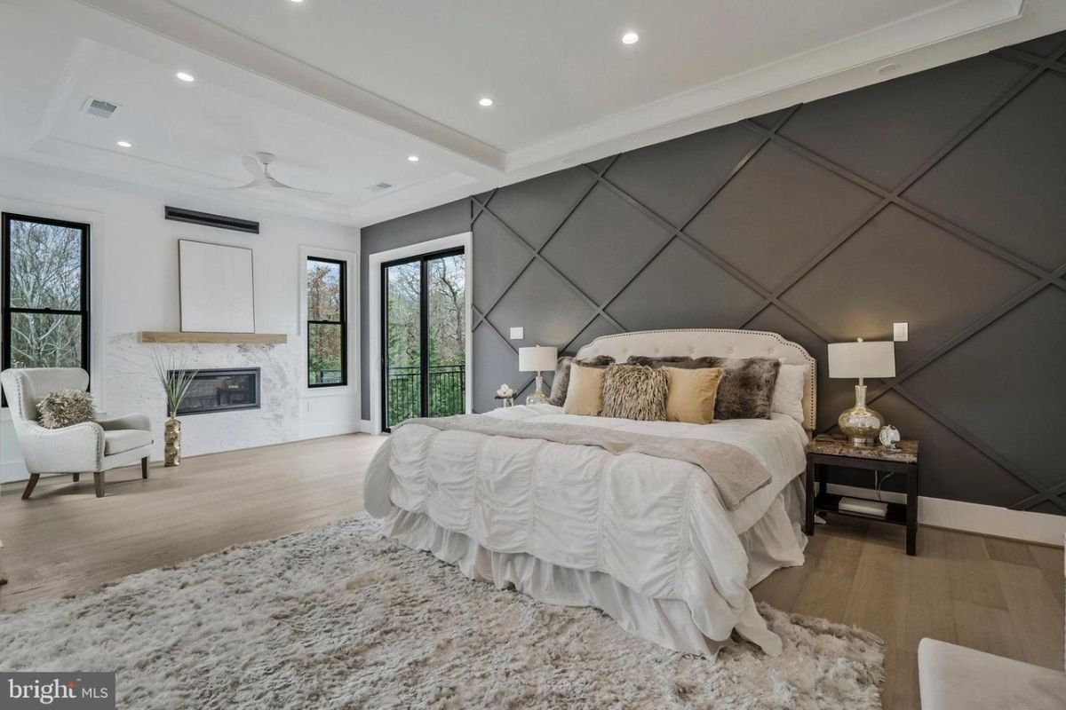 A bedroom with a bed, nightstand, chair, windows, and a rug.