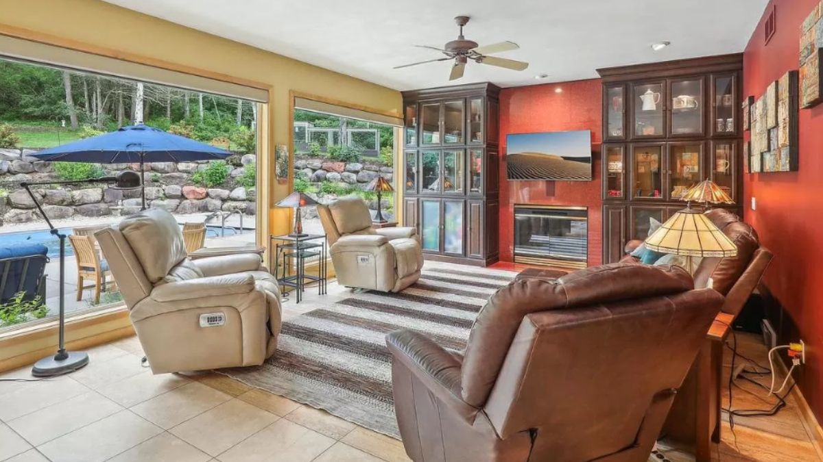 A living room with a fireplace, cabinets, a rug, a couch, and chairs.