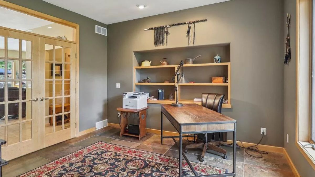 A home office with shelves, a rug, a desk, and a chair.