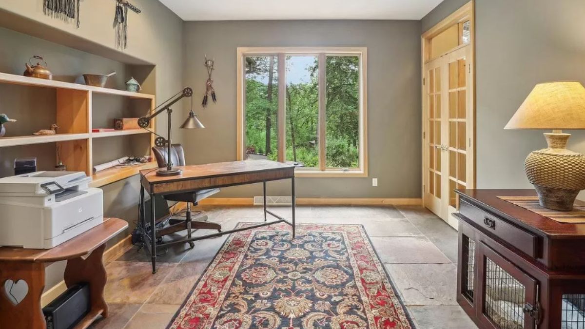 A home office with shelves, a rug, a desk, cabinet and a chair.