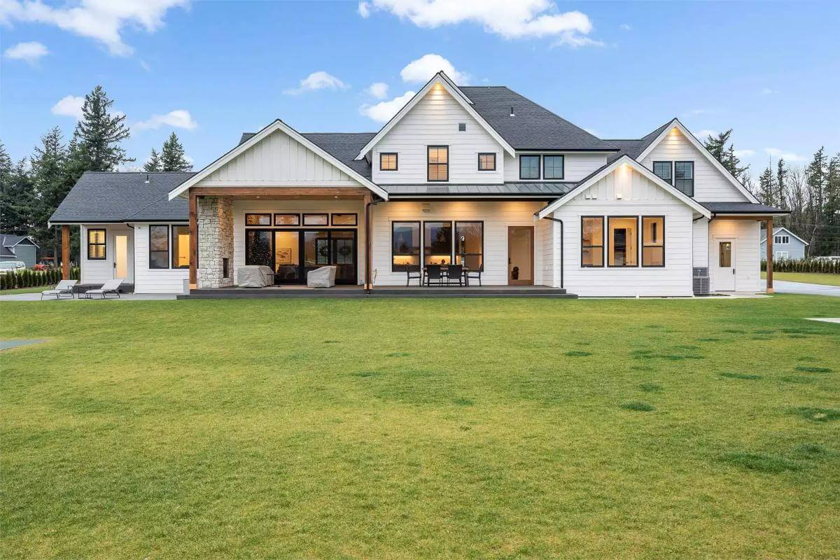 Rear view with multiple gables, a covered patio, and a multitude of windows.