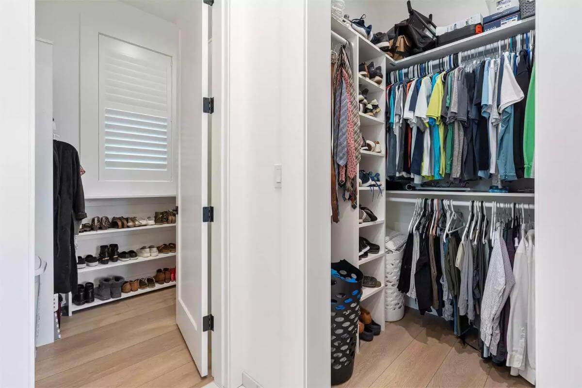 Dual primary walk-in closets with white built-ins and a hardwood floor.