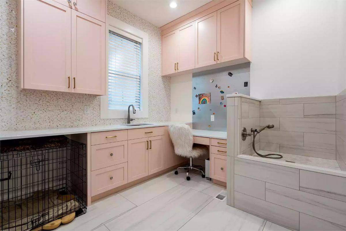 Laundry room with pink cabinets, a built-desk, and a dog wash.