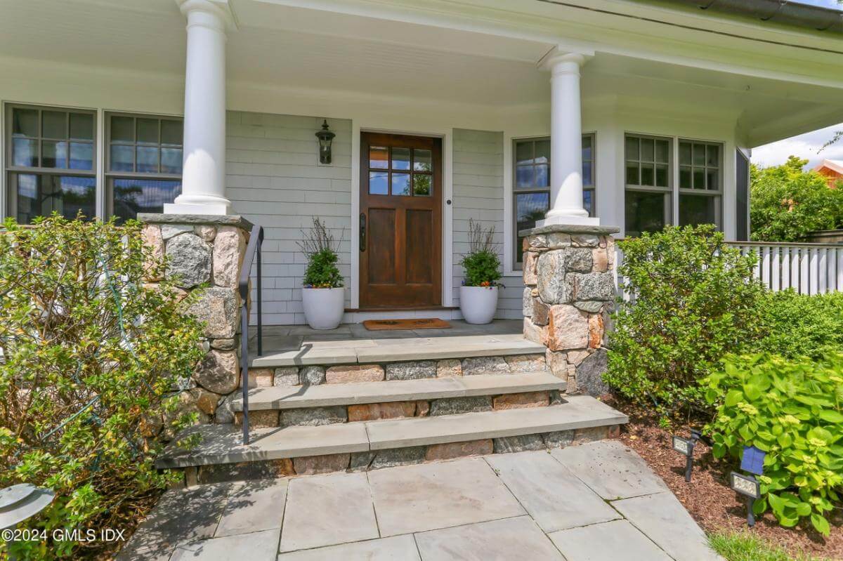 Front entry with a stoop, stone base columns, and a glazed front door.