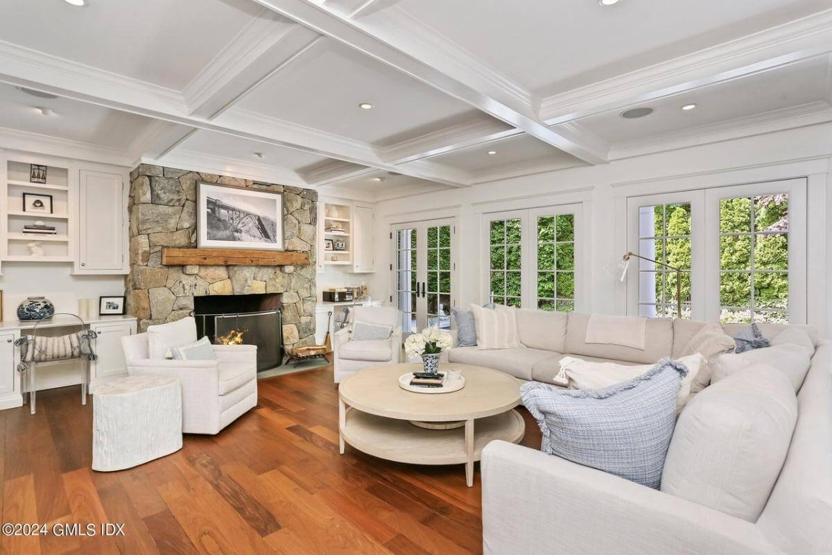 Family room with an L-shaped soda and a stone fireplace under a coffered ceiling.