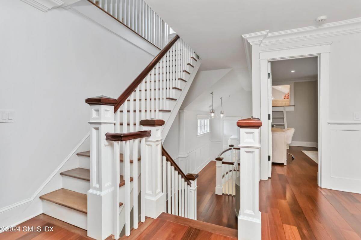 Staircase with white railings leading to the upstairs bedrooms and playroom.