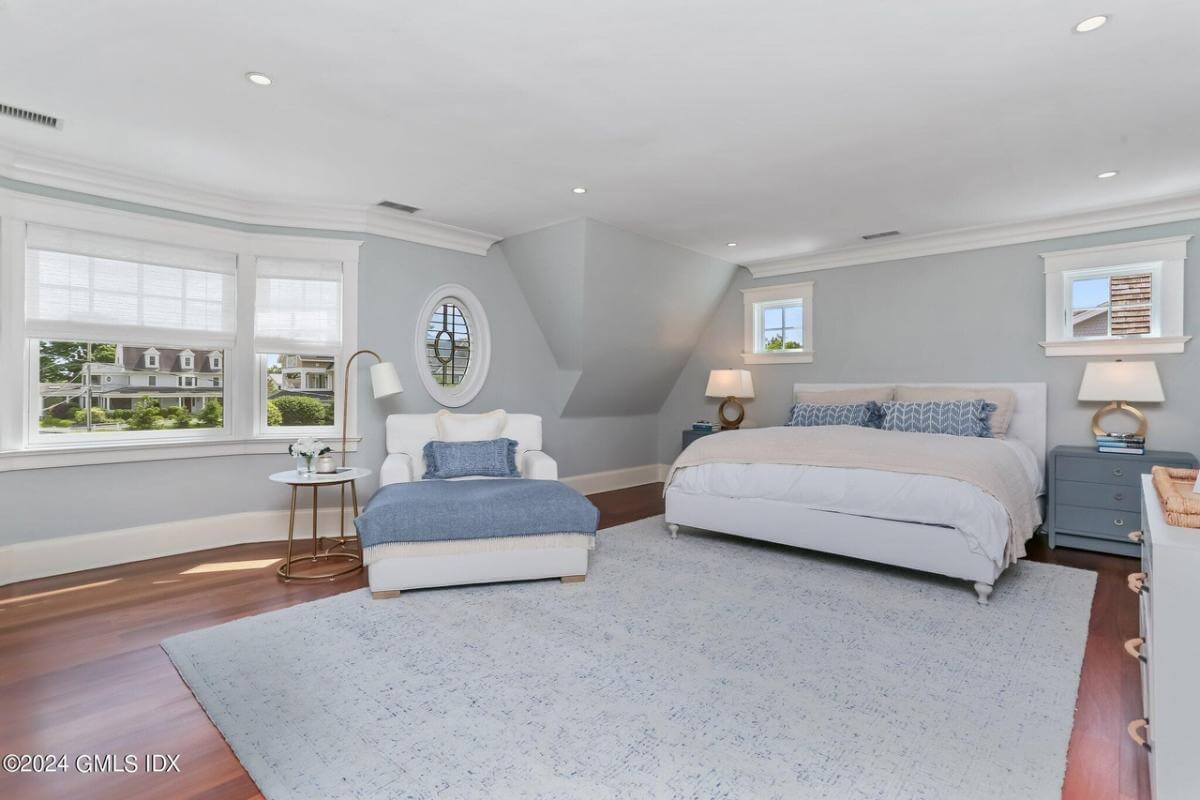 Primary bedroom with an upholstered bed and a lounge chair over the gray area rug.