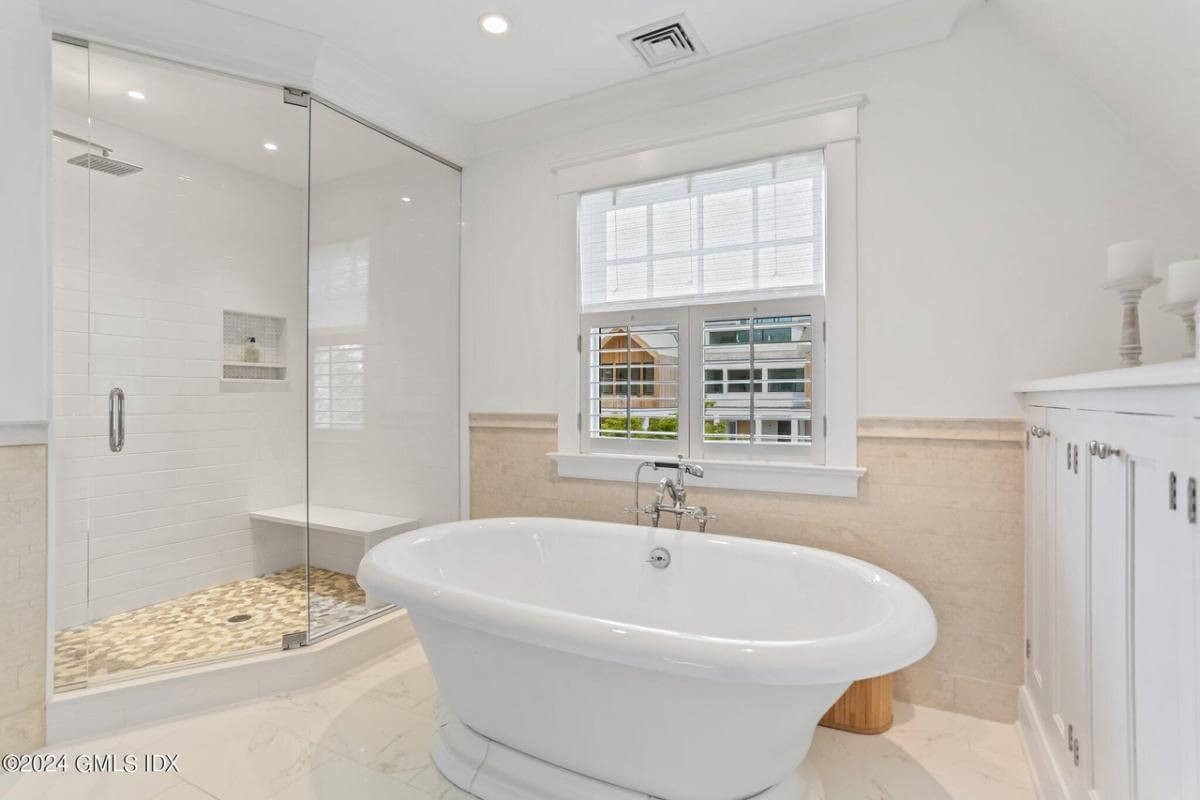 Primary bathroom with a white vanity, a soaking tub, and a walk-in shower with a tiled bench.