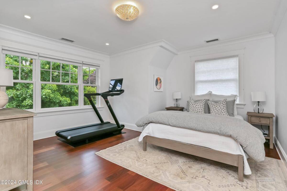 Bedroom with hardwood flooring and a vaulted wall.