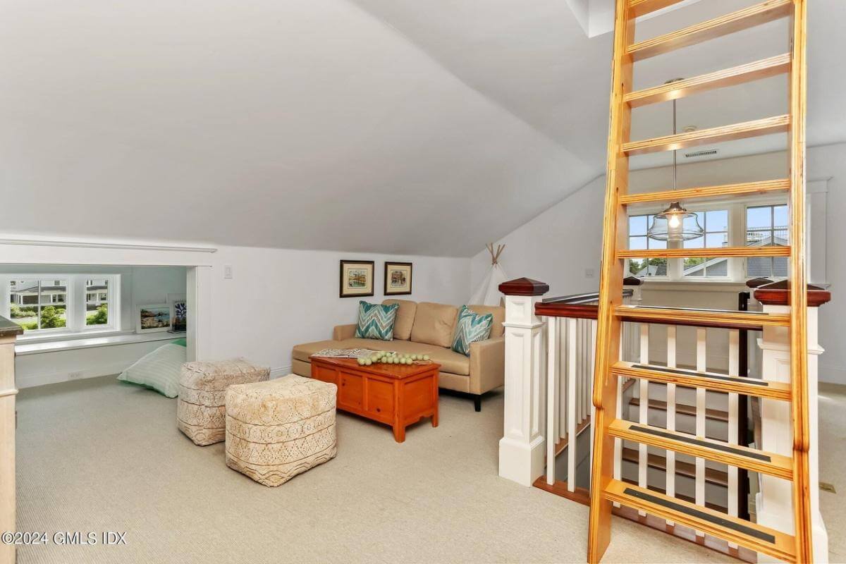 Loft with a leather sofa, a couple of stools, and a ladder leading to the playroom.