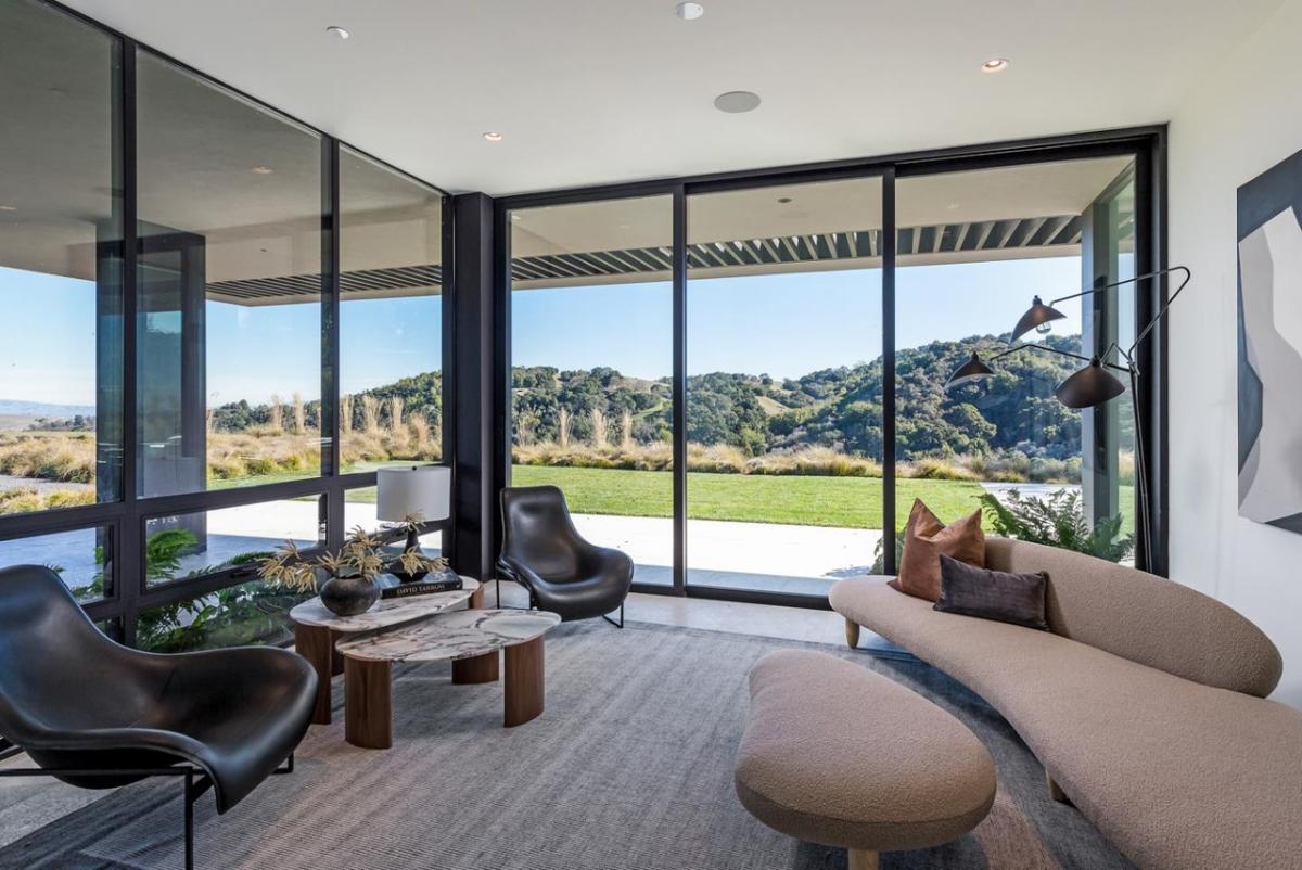 Living room with couches and glass walls.