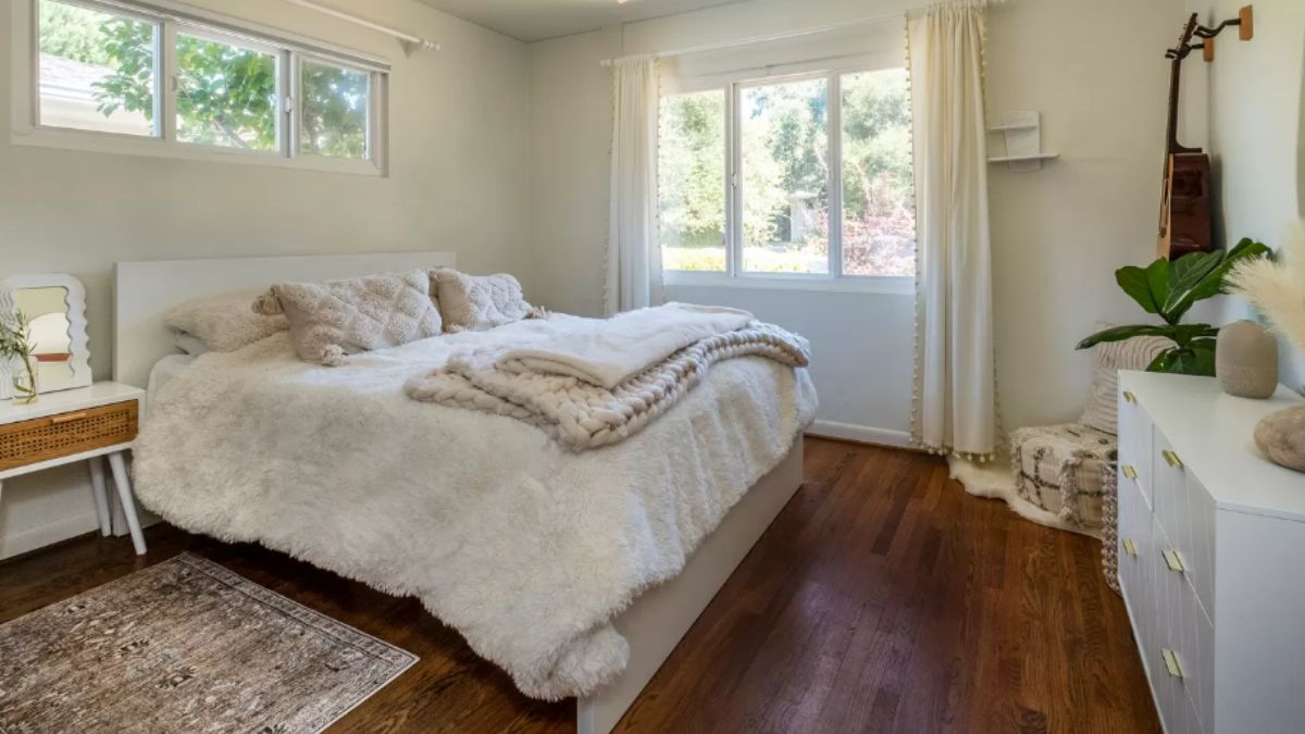 A bedroom with a bed, nightstand, a window, and a cabinet.