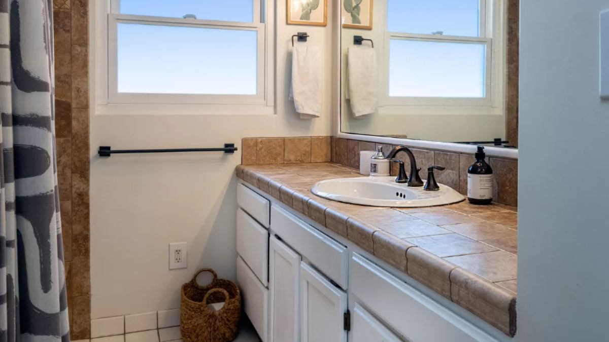 A bathroom with a vanity, mirror, and cabinets.