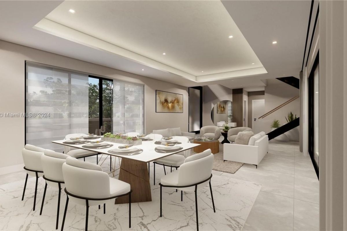 A dining area with a table surrounded by chairs and a living area.