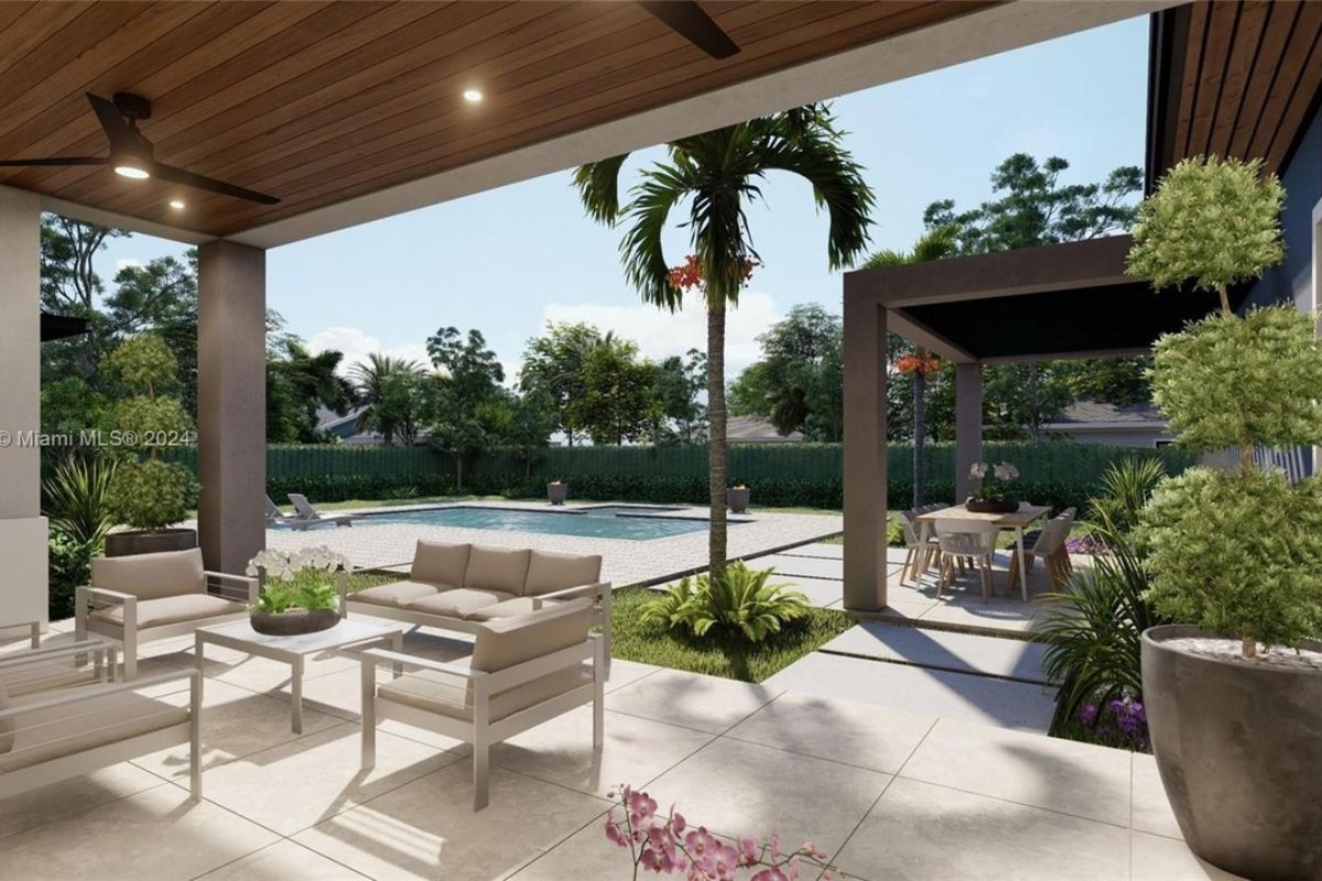 A patio with plants and a coffee table surrounded by chairs.