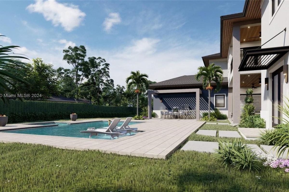 A swimming pool with a wooden poolside surrounded by plants and trees.