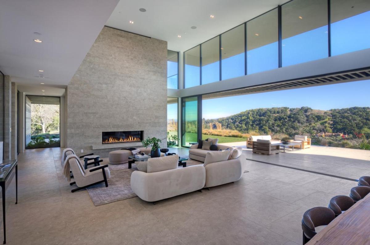 Living room with high ceilings, couches and a fireplace.