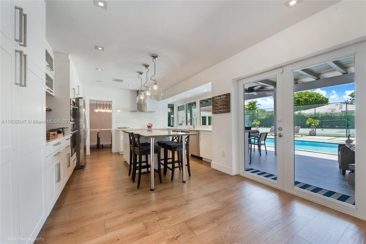 A kitchen with a table, chairs, countertops, and cabinets.