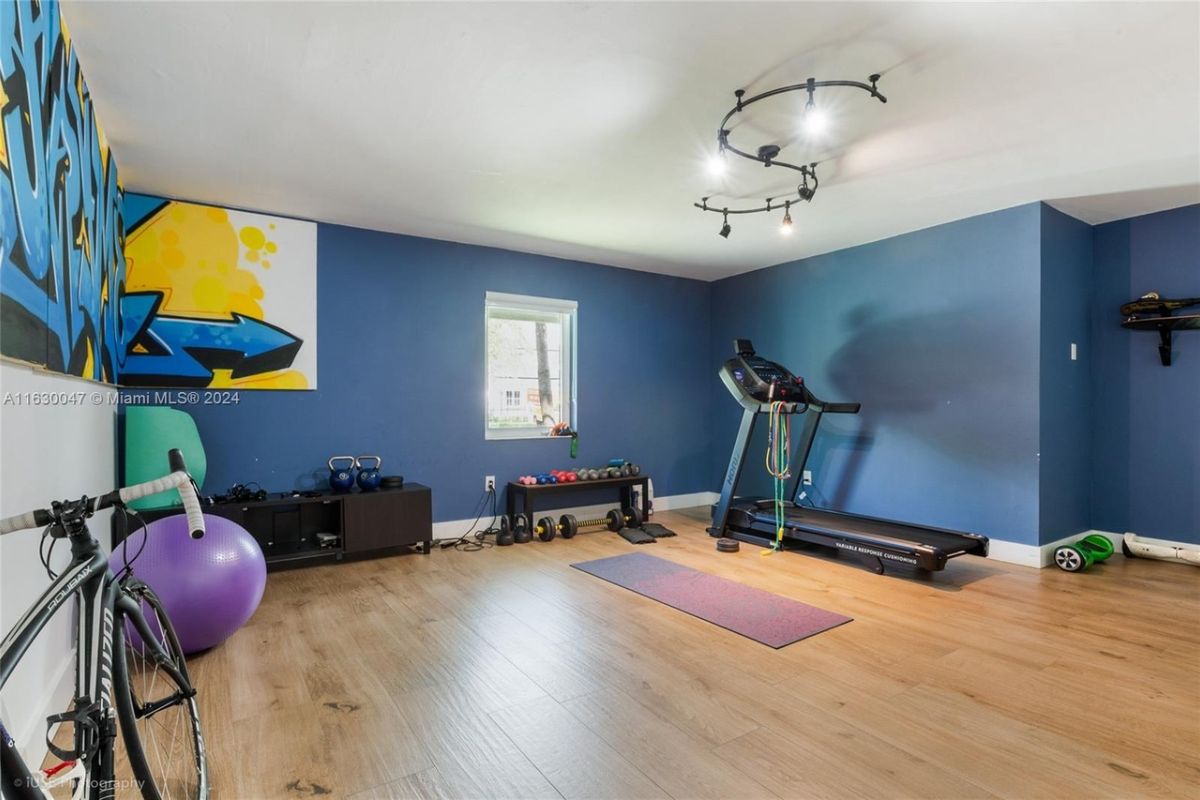 A home gym with blue walls, a window, and gym equipment.