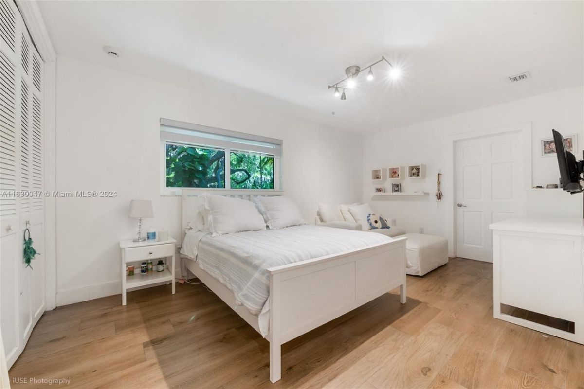 A bedroom with a bed, a window, nightstands, and a TV.