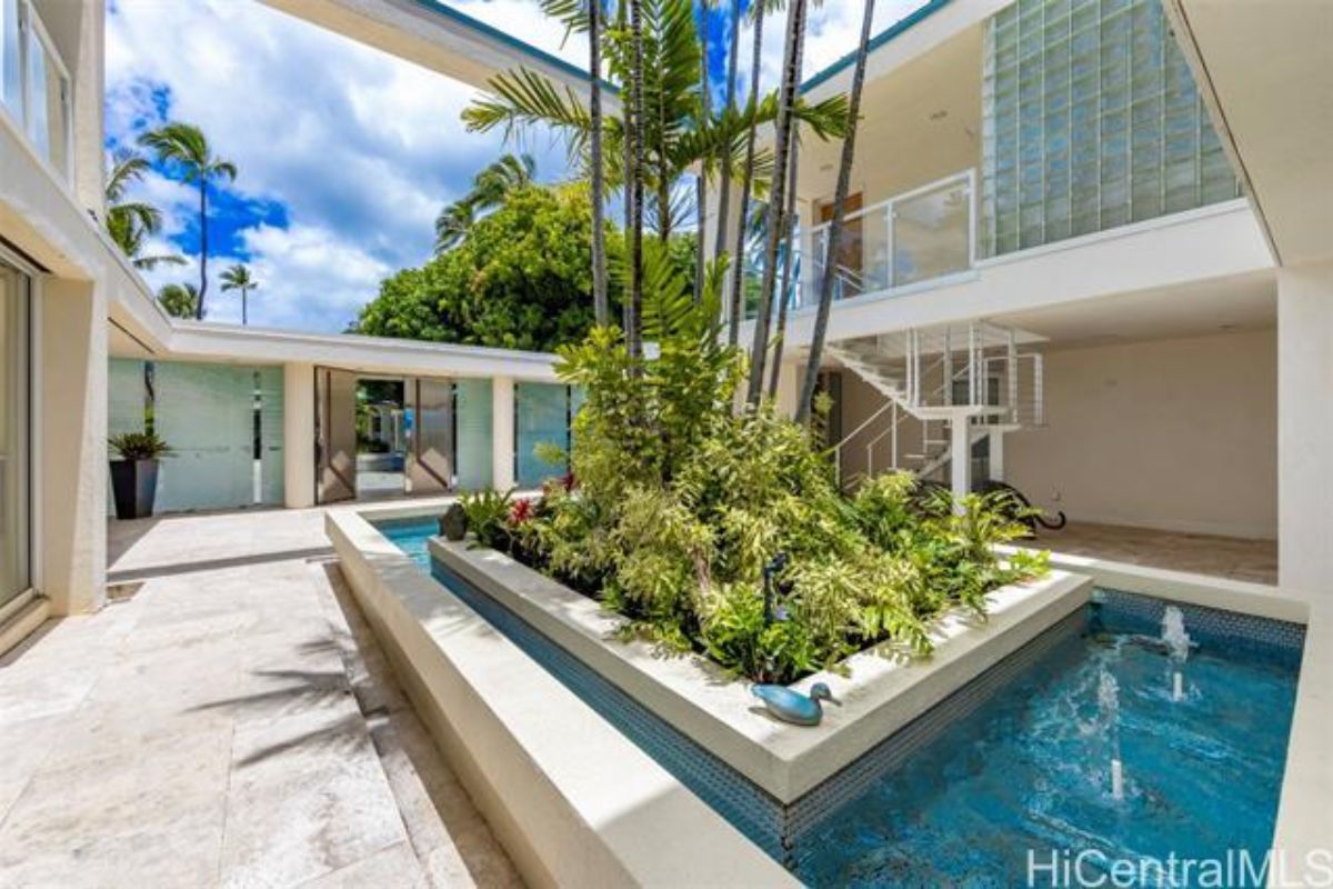 A courtyard with a pool and plants in the center.