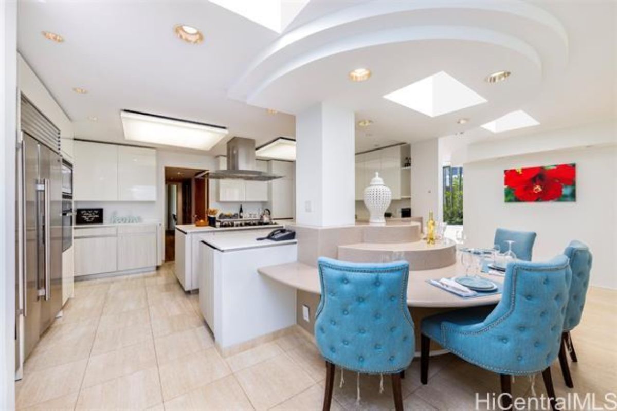 A kitchen with countertops, chairs, cabinets, and kitchen appliances.