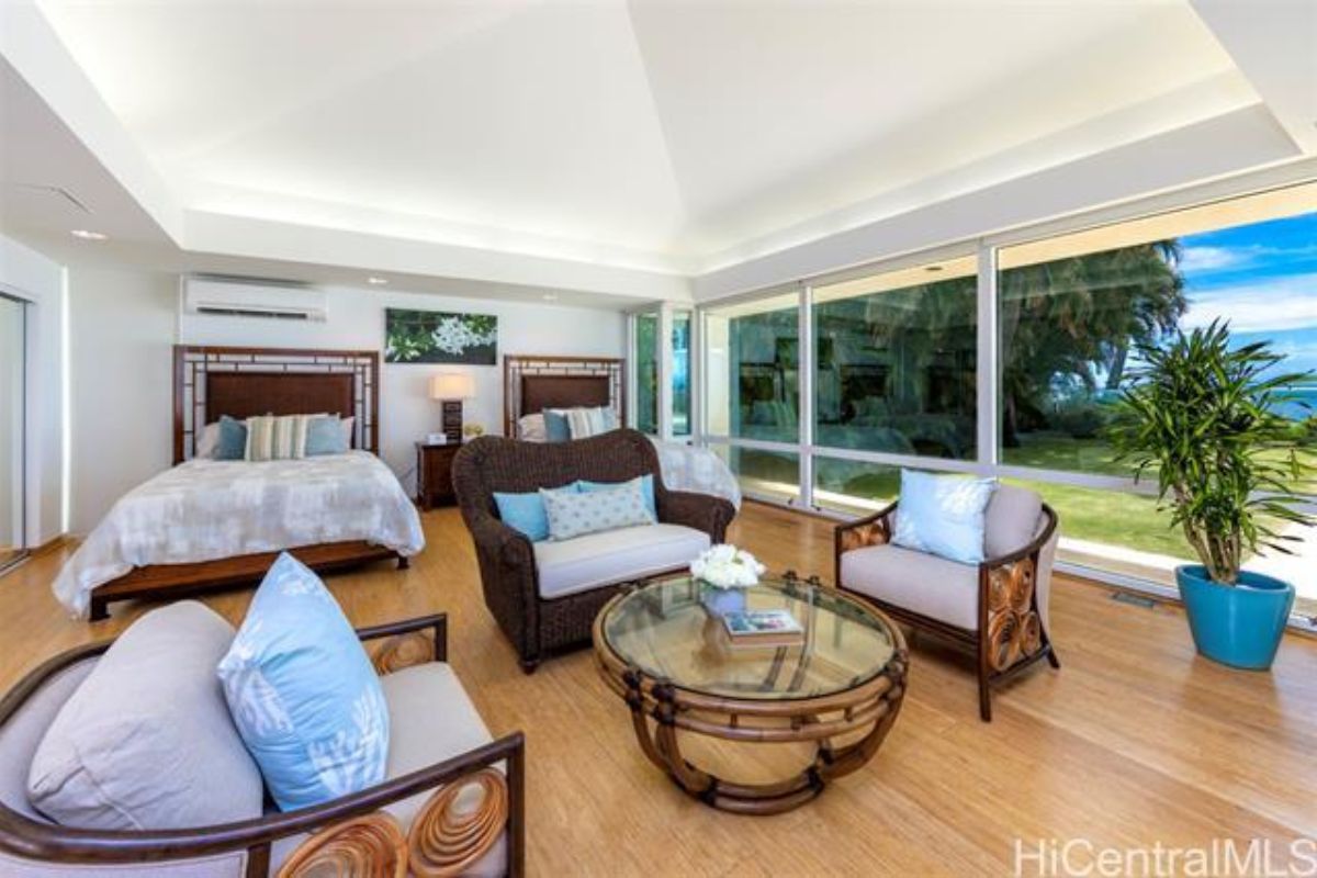 A bedroom with two beds, a nightstand, a window, a couch, chairs, and a center table.