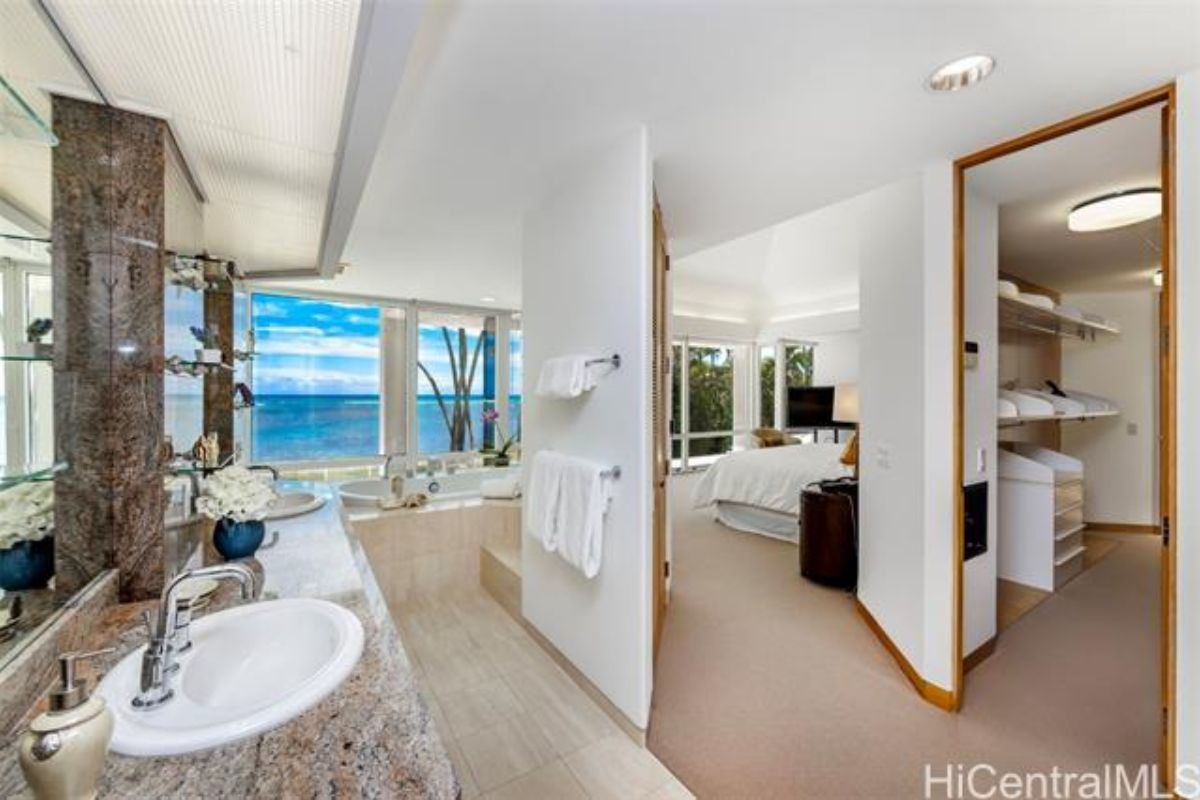 A bathroom with a window, dual vanity, and a bathtub.