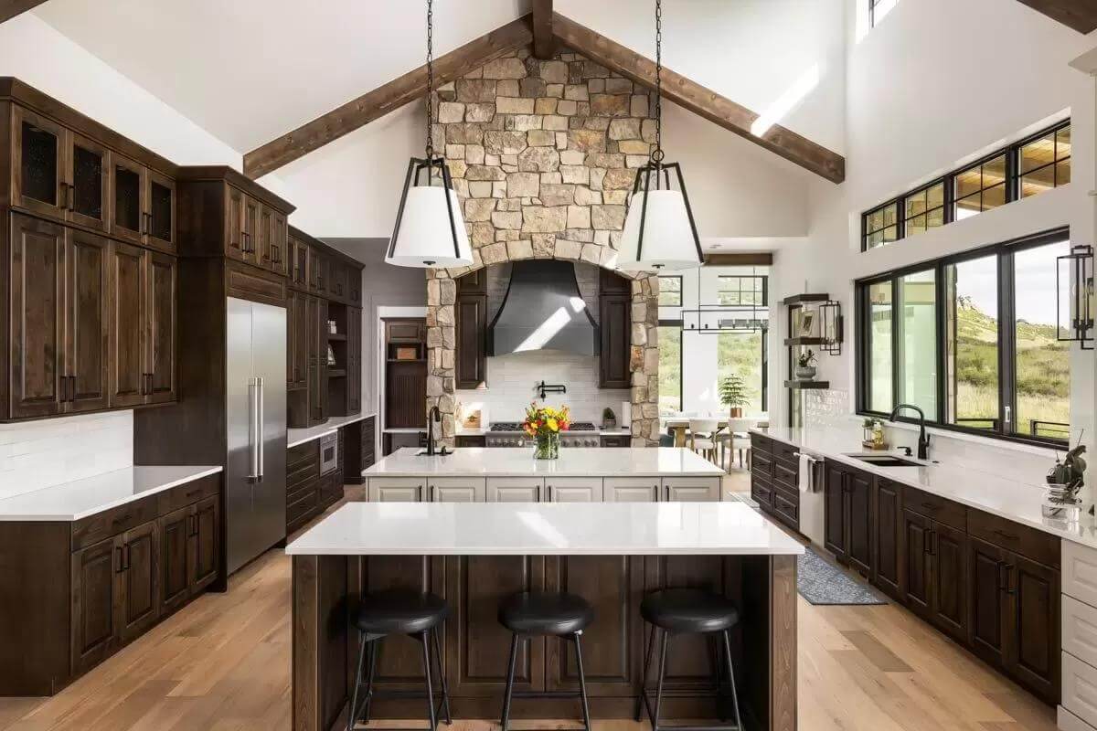 Kitchen with wooden cabinets, two islands, and a cathedral ceiling with exposed beams.