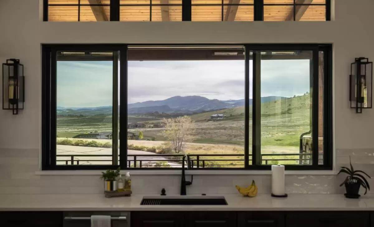 The kitchen includes a prep sink and large windows overlooking the surrounding landscape.