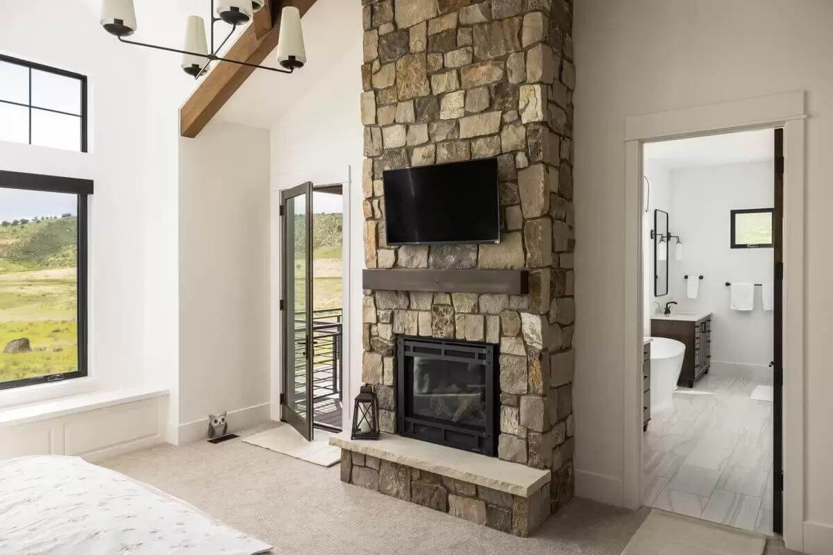 The primary bedroom includes an ensuite bath and a stone fireplace with a TV on top.