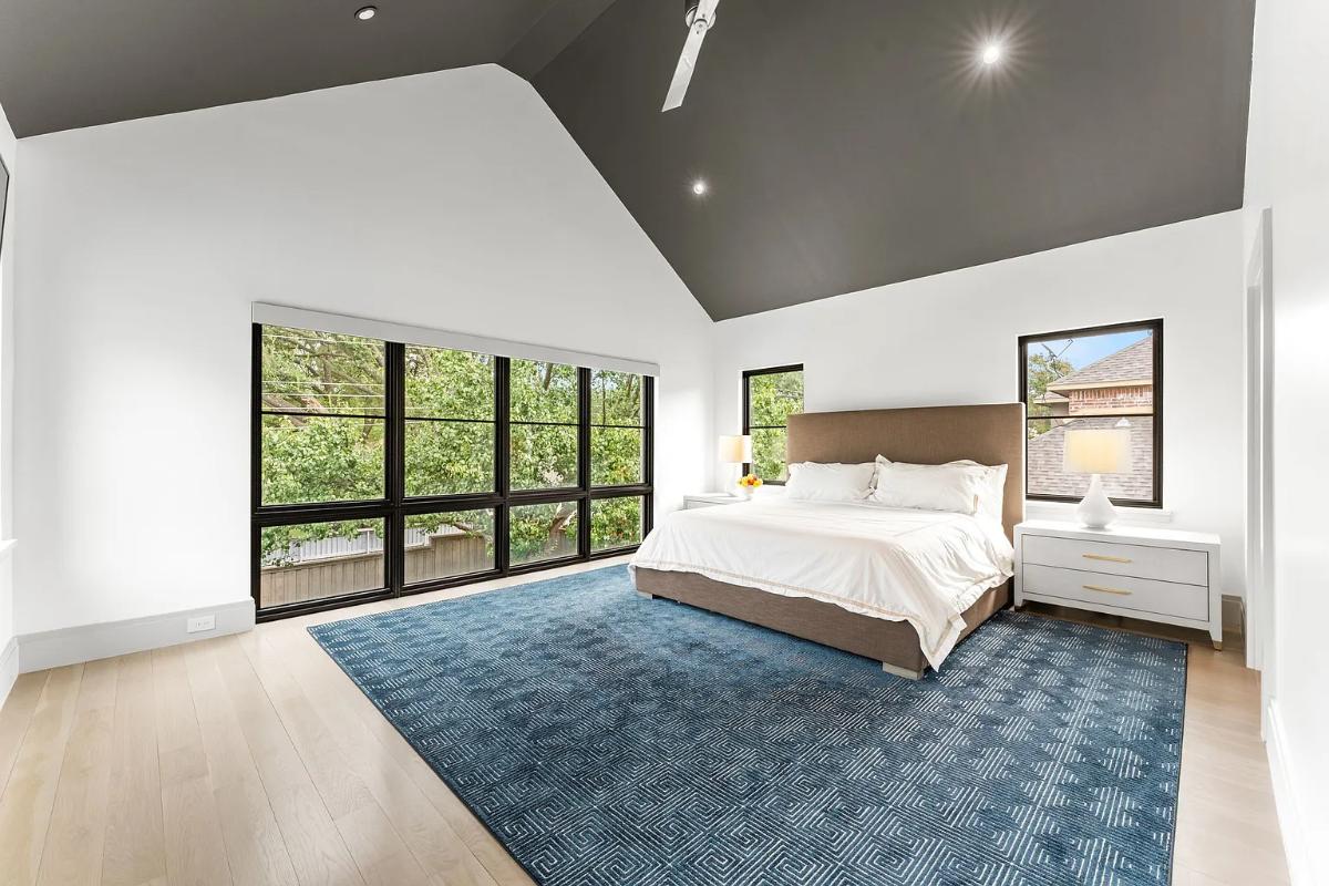 Bedroom with a large bed, glass windows and hardwood floors.