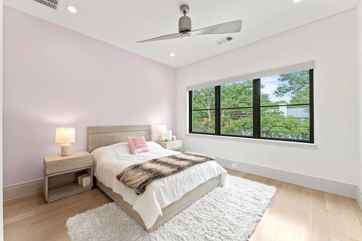 Bedroom with a large bed, glass windows and hardwood floors.